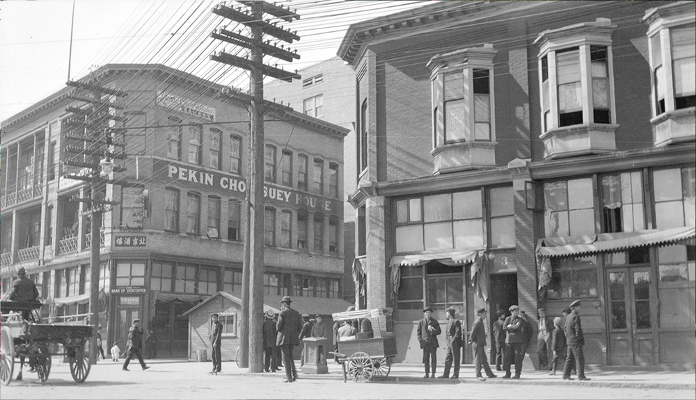 1910: People congregate on the street near the Chinese Freemasons Building at left. (Vancouver Archives)