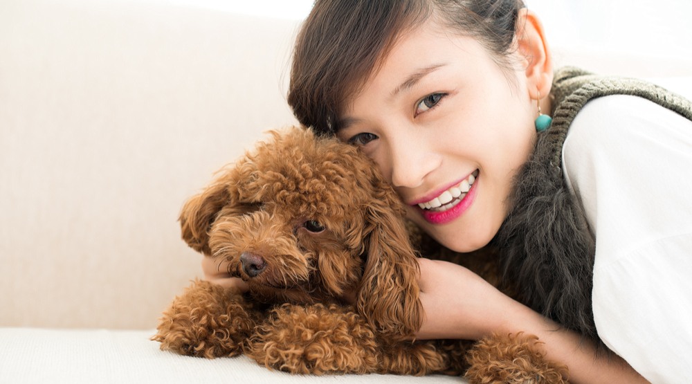 Woman cuddling dog (Dragon Images/Shutterstock)