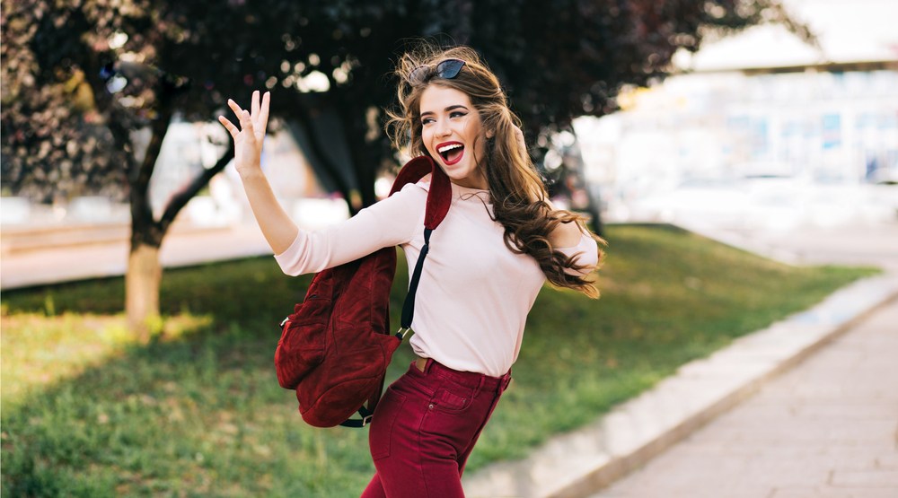 Woman walking looking happy waving (vfedorchenko/Shutterstock)