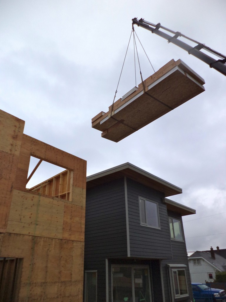 Image: During construction the lowering of the structural insulating panel (SIP) roof system.